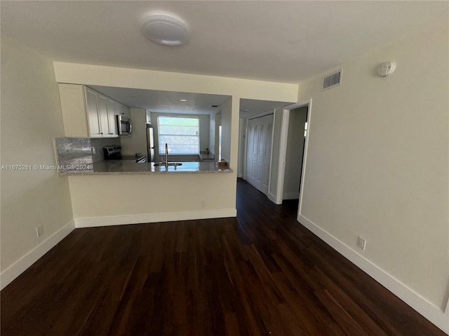 kitchen with kitchen peninsula, white cabinets, dark hardwood / wood-style flooring, appliances with stainless steel finishes, and sink