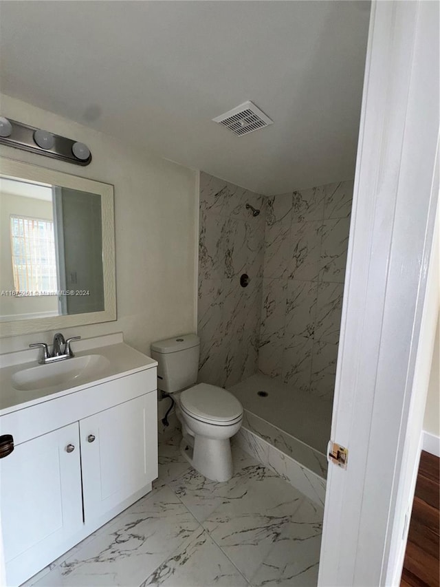 bathroom with vanity, a tile shower, and toilet