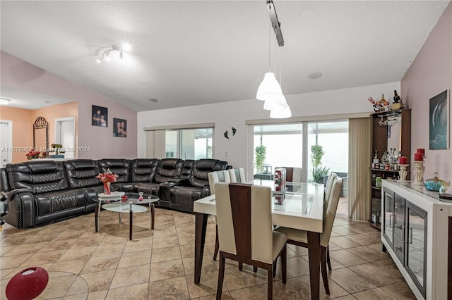 dining room featuring lofted ceiling, a textured ceiling, and light tile patterned floors