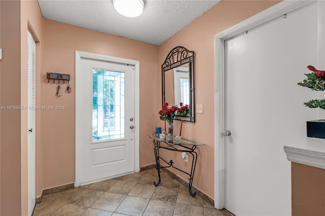 entryway with a textured ceiling and light tile patterned floors