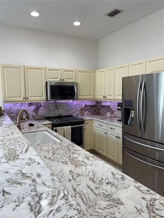 kitchen featuring sink, appliances with stainless steel finishes, cream cabinetry, and backsplash