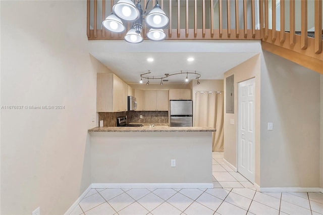 kitchen with kitchen peninsula, decorative backsplash, light brown cabinets, appliances with stainless steel finishes, and light stone counters