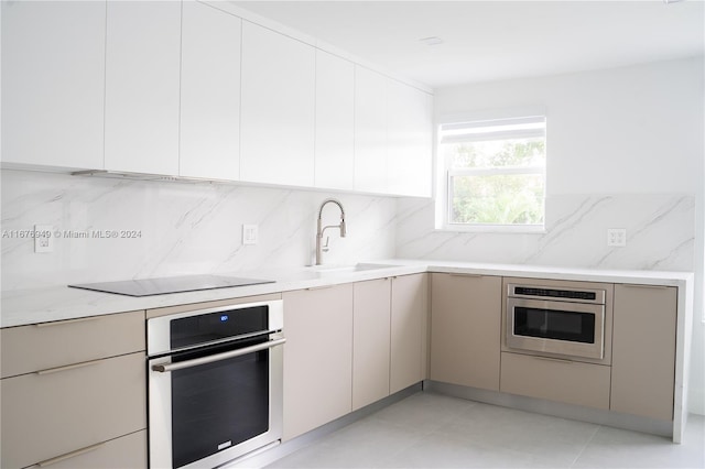 kitchen featuring oven, black electric cooktop, decorative backsplash, and sink