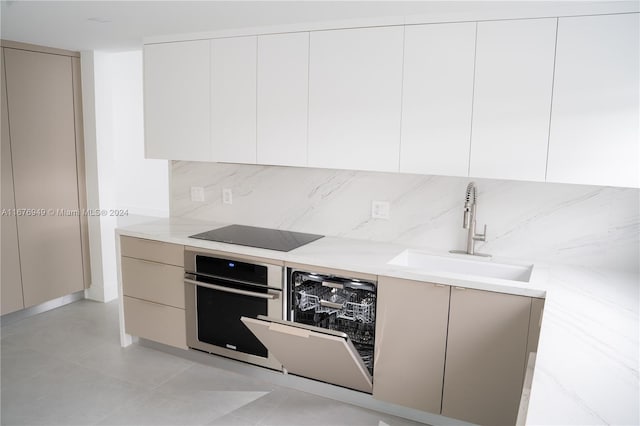 kitchen featuring stainless steel appliances, sink, light stone countertops, light tile patterned floors, and tasteful backsplash