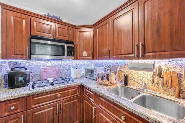 kitchen featuring sink, decorative backsplash, light stone counters, and stainless steel appliances