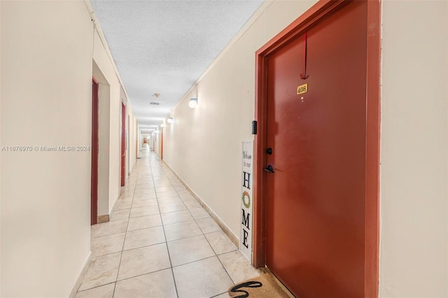 hall featuring a textured ceiling and light tile patterned flooring