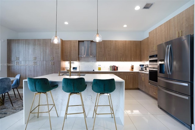 kitchen with appliances with stainless steel finishes, wall chimney exhaust hood, hanging light fixtures, and a breakfast bar area