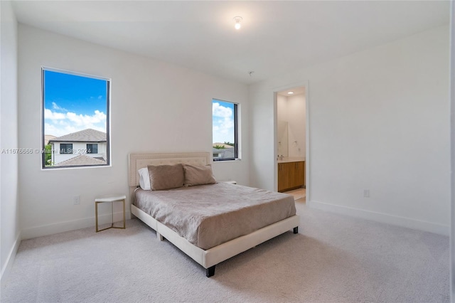 bedroom featuring ensuite bathroom and carpet flooring