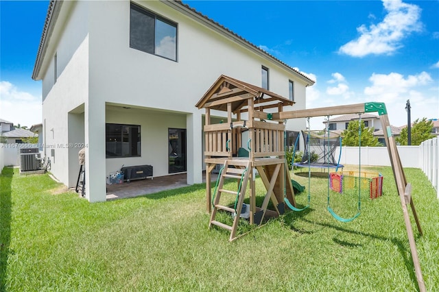 view of jungle gym featuring central air condition unit, a patio, a yard, and a trampoline