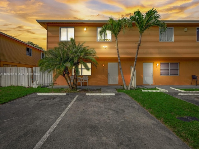 view of property featuring stucco siding, uncovered parking, and fence