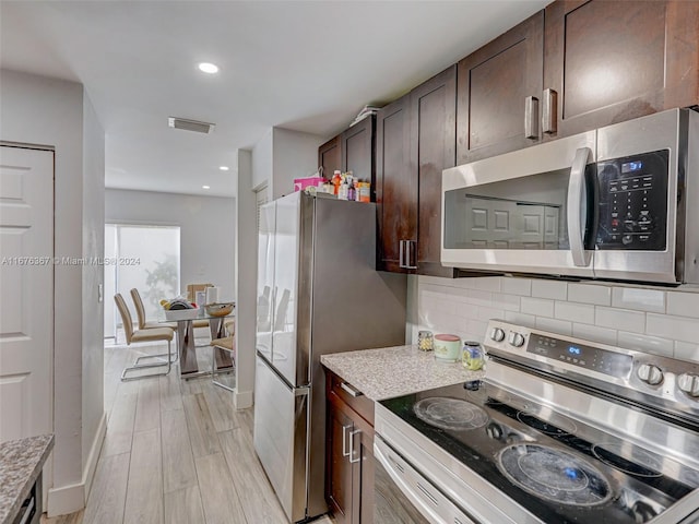 kitchen with dark brown cabinets, backsplash, light stone countertops, light hardwood / wood-style floors, and stainless steel appliances