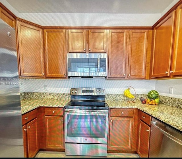 kitchen with appliances with stainless steel finishes, light stone counters, and tasteful backsplash