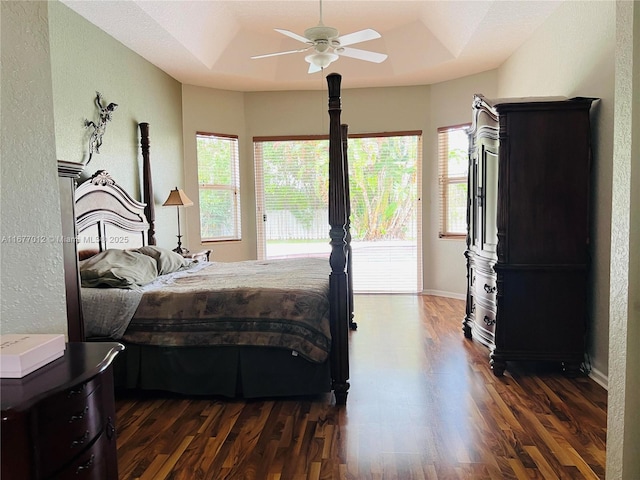 bedroom with a raised ceiling, ceiling fan, access to exterior, and dark wood-type flooring