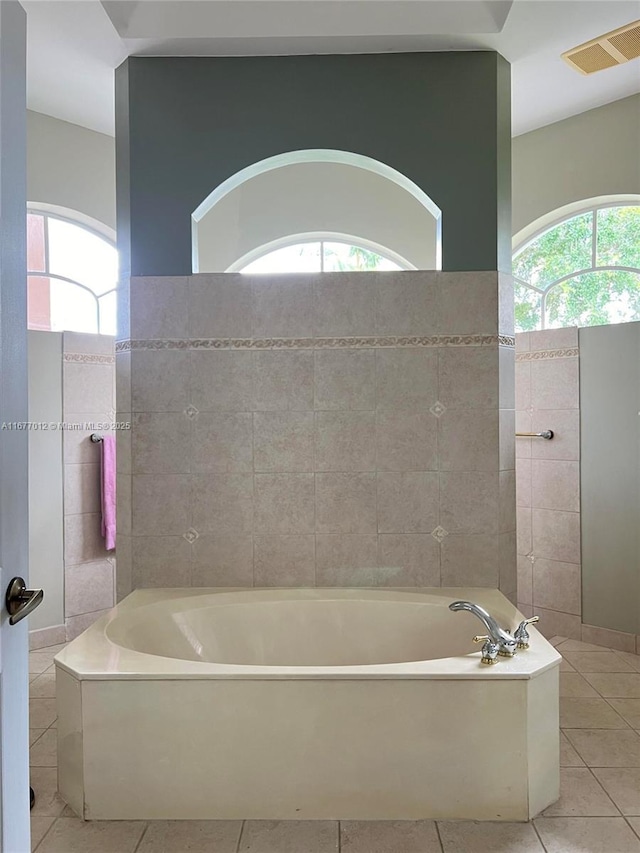 bathroom with a bathing tub, tile patterned flooring, and tile walls