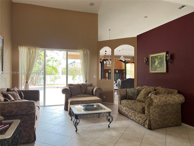 tiled living room featuring ceiling fan and a high ceiling