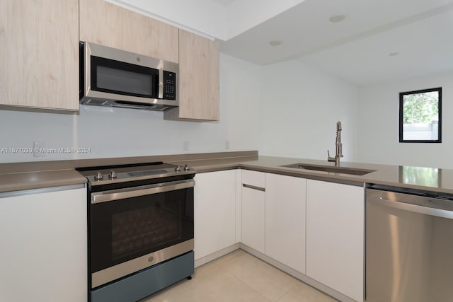 kitchen with sink, stainless steel appliances, and light tile patterned floors