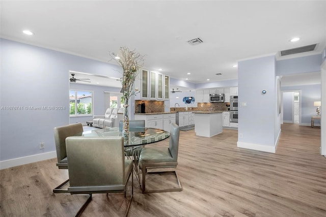 dining room with ceiling fan, light hardwood / wood-style floors, sink, and crown molding