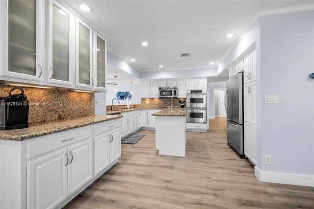 kitchen featuring a center island, white cabinets, light wood-type flooring, light stone countertops, and appliances with stainless steel finishes