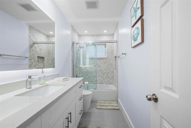 full bathroom featuring combined bath / shower with glass door, tile patterned floors, vanity, and toilet