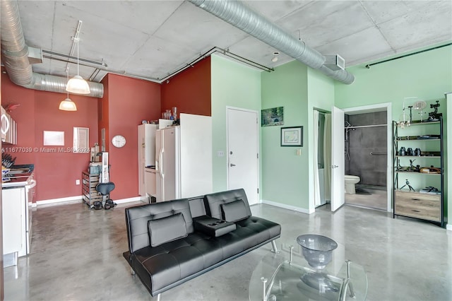 living room featuring a towering ceiling and concrete flooring