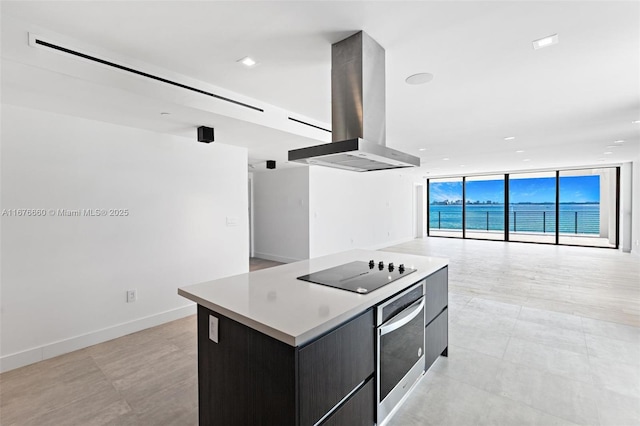 kitchen with island range hood, modern cabinets, a kitchen island, open floor plan, and stainless steel oven