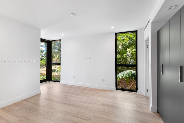 unfurnished room with light hardwood / wood-style floors and expansive windows