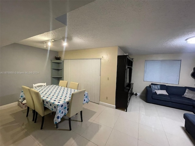 dining space with a textured ceiling, light tile patterned flooring, and rail lighting