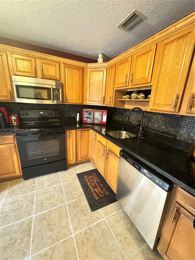 kitchen featuring light tile patterned flooring, decorative backsplash, stainless steel appliances, and sink