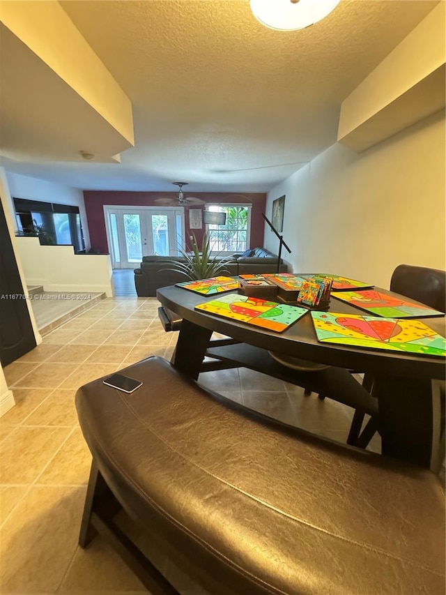 recreation room featuring ceiling fan, a textured ceiling, and tile patterned flooring