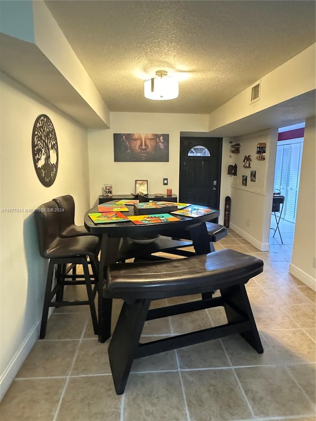 rec room with a textured ceiling and tile patterned floors