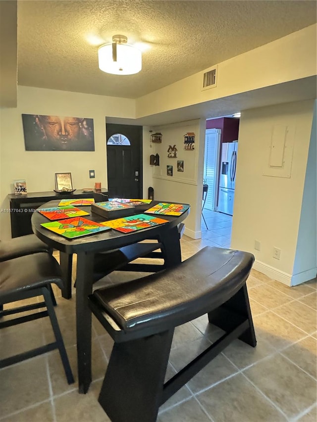 recreation room featuring light tile patterned flooring and a textured ceiling