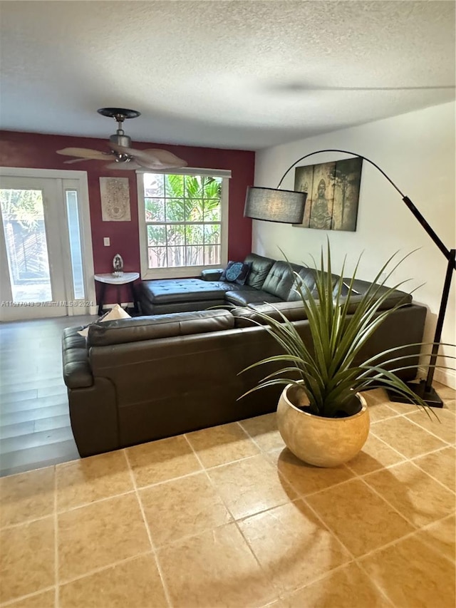 tiled living room with a textured ceiling and ceiling fan