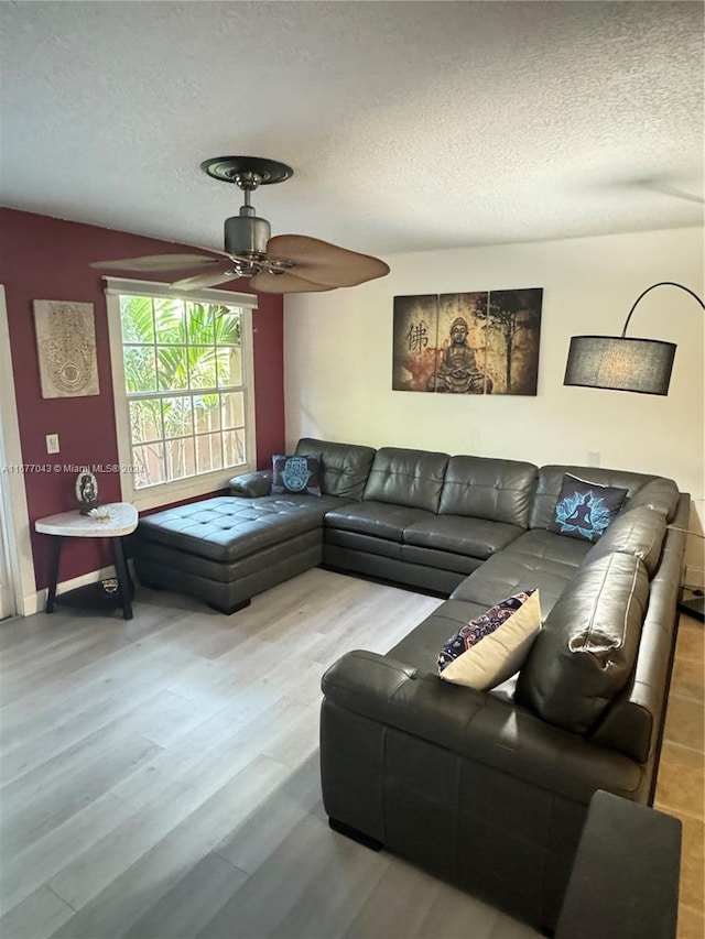 living room featuring a textured ceiling, wood-type flooring, and ceiling fan