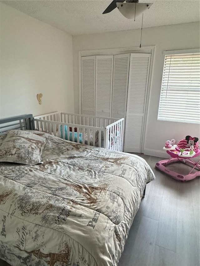 bedroom featuring hardwood / wood-style floors, a textured ceiling, a closet, and ceiling fan