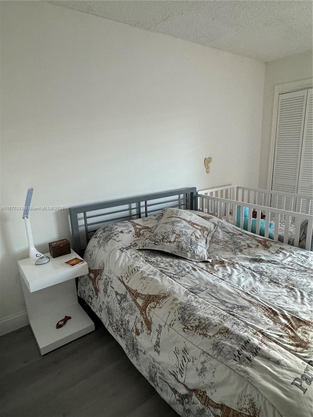 bedroom featuring a textured ceiling and dark hardwood / wood-style floors