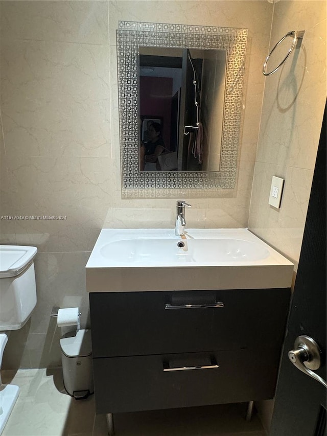 bathroom with tile walls, vanity, and toilet