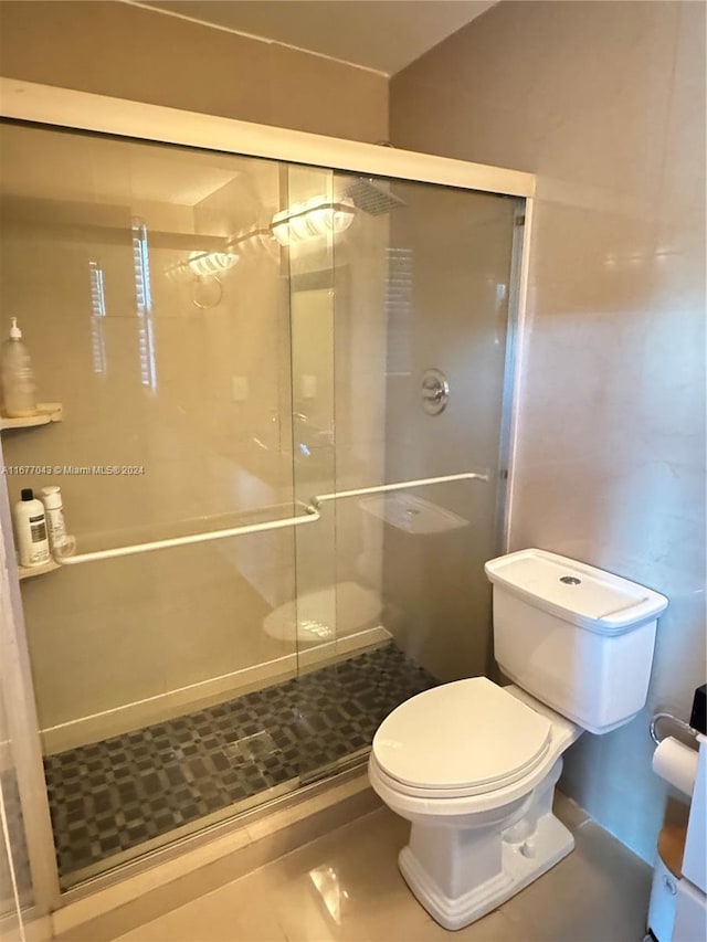 bathroom with toilet, an enclosed shower, and tile patterned floors