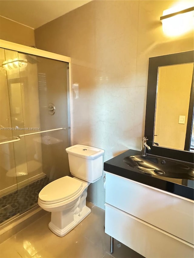 bathroom featuring toilet, a shower with shower door, and vanity