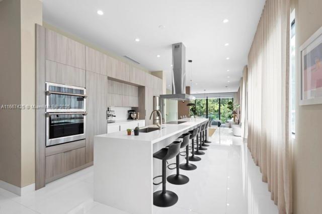 kitchen with exhaust hood, sink, stainless steel fridge, pendant lighting, and light tile patterned floors