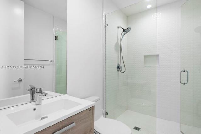 bathroom featuring vanity, toilet, and a shower with shower door