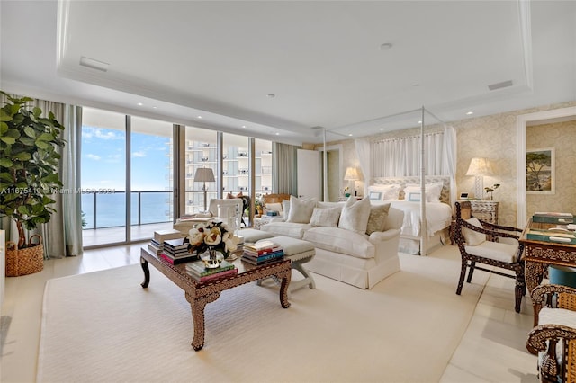 living room with a water view, a raised ceiling, and expansive windows