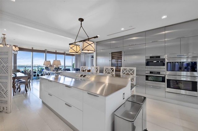 kitchen with a large island, pendant lighting, stainless steel double oven, and floor to ceiling windows