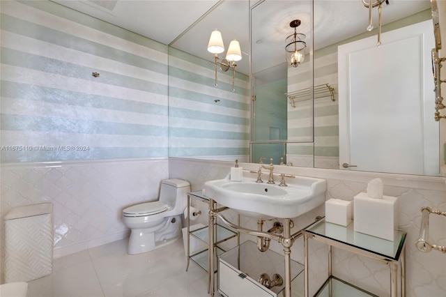 bathroom with tile walls, sink, toilet, and tile patterned flooring