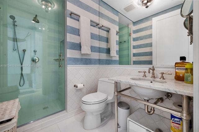 bathroom featuring toilet, tile patterned flooring, a shower with shower door, tile walls, and vanity