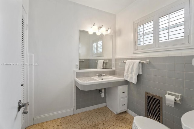 bathroom featuring sink, tile walls, and toilet