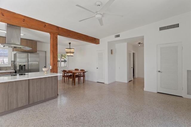 kitchen with stainless steel fridge, island range hood, decorative light fixtures, and a healthy amount of sunlight