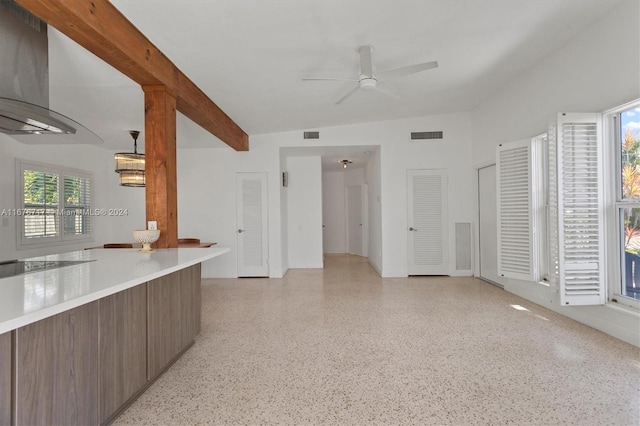 unfurnished living room with a wealth of natural light, ceiling fan, and lofted ceiling with beams