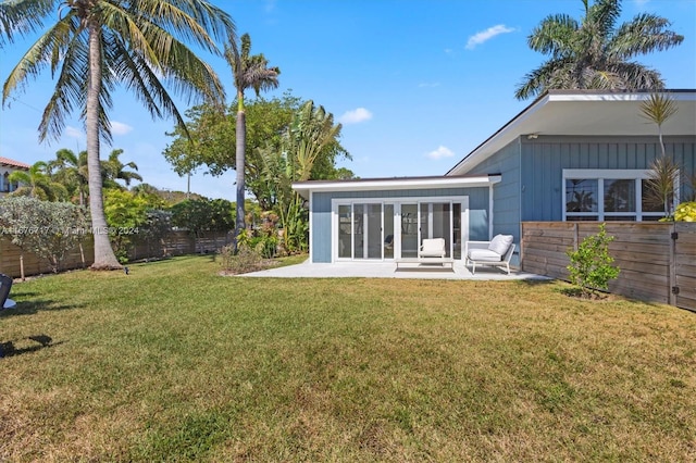 back of house featuring a lawn, a sunroom, and a patio