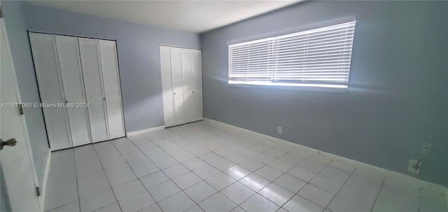 unfurnished bedroom featuring two closets and light tile patterned floors