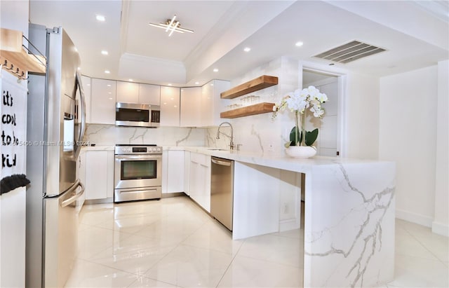 kitchen featuring decorative backsplash, white cabinets, light stone countertops, crown molding, and stainless steel appliances